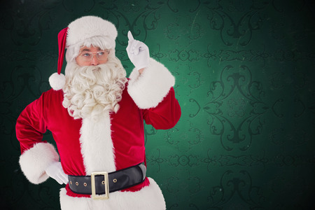 Serious santa claus pointing his finger against elegant patterned wallpaper in red tonesの写真素材