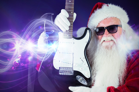 Father Christmas shows a guitar against curved laser light design in purpleの写真素材