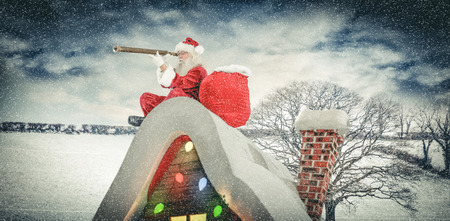 Santa sitting on roof of cottage against snow sceneの写真素材