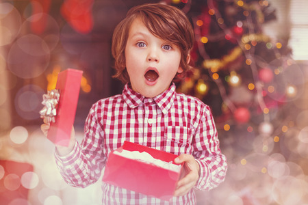 Glowing background against surprised little boy holding a giftの写真素材