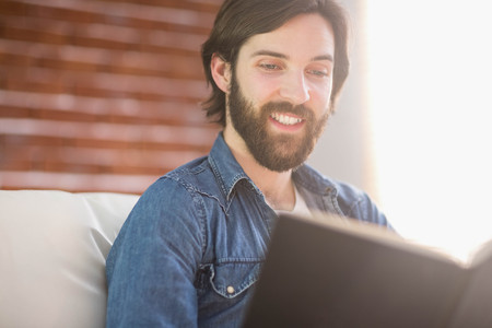 Casual man reading on his sofa at home in the living roomの写真素材