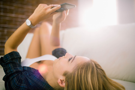 Pretty blonde on the phone at home in the living roomの写真素材