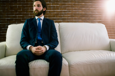 Businessman sitting on the couch at home in the living roomの写真素材