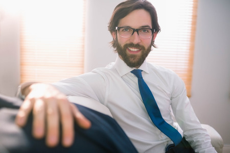 Happy businessman sitting on couch at home in the living roomの写真素材