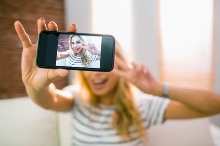Pretty blonde taking a selfie at home in the living room