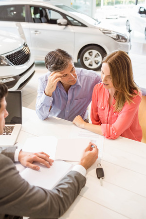Smiling couple buying a new car at new car showroomの写真素材