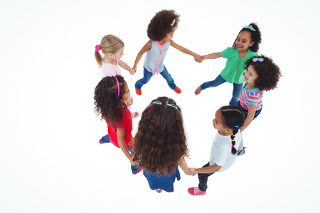 Smiling girls all holding each others hands against a white backgroundの写真素材