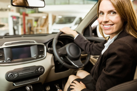 Smiling businesswoman siting in a car at new car showroom