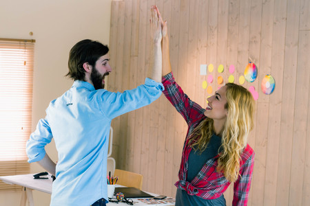 Creative team high fiving in casual office