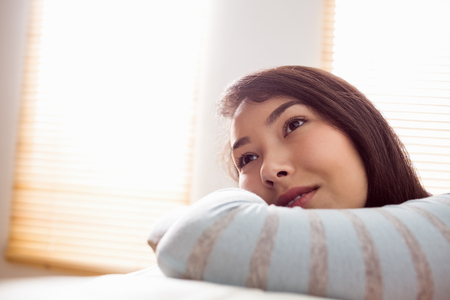 Asian woman relaxing on couch at home in the living roomの写真素材
