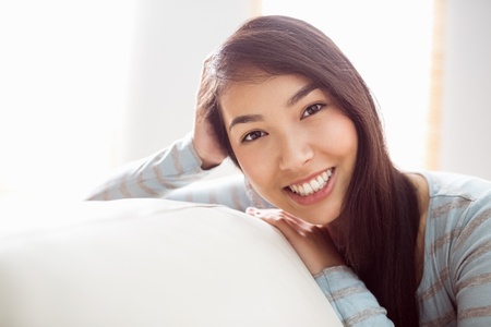Asian woman relaxing on couch at home in the living roomの写真素材