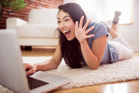 Asian woman using laptop on floor at home in the living roomの写真素材