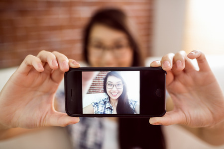 Asian woman on the couch taking selfie at home in the living room