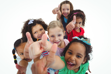Smiling girls all looking upwards with thumbs up against a white backgroundの写真素材