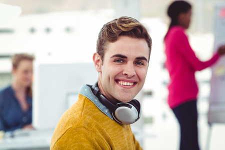Graphic designer wearing headphones at desk in casual officeの写真素材