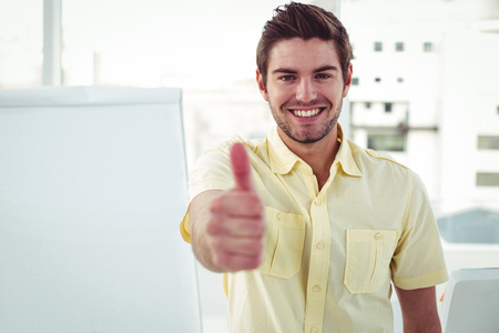 Smiling creative businessman by his desk in casual officeの写真素材
