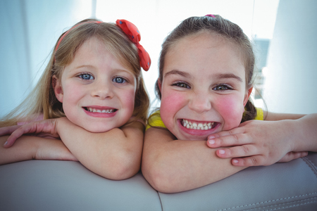Happy kids looking from the back of the couch and smilingの写真素材