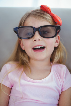 Close up of a girl wearing 3d glasses for a moive on the couchの写真素材