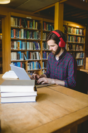 Hipster student studying in library at the universityの写真素材