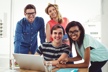 Creative business team working hard together on laptop in casual office
