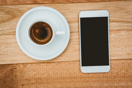 Above view of a coffee and a smartphone on wood deskの写真素材