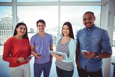 Young creative team looking at phones and tablets in casual officeの写真素材