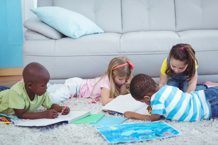 Smiling kids drawing pictures on paper on the floorの写真素材