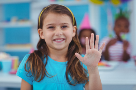 Happy kid at a birthday party holding up her handの写真素材