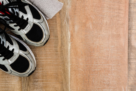 Running shoes and a towel on wooden tableの写真素材