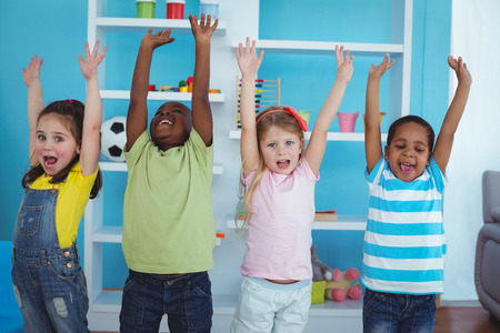 Happy kids with arms raised together in the bedroom