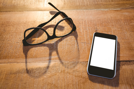 Close up view of smartphone and glasses on wood plankの写真素材