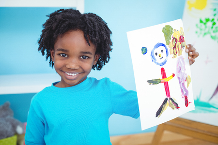 Happy kid enjoying arts and crafts painting at their deskの写真素材