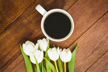 White flowers and a cup of coffee on wood deskの写真素材