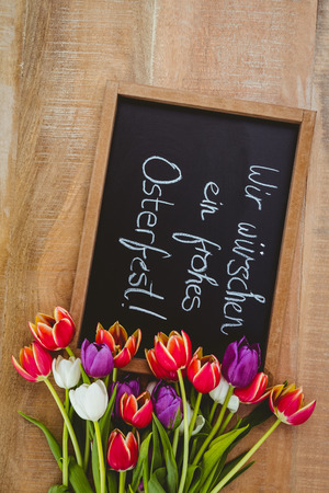 Bouquet of colored flowers against black board on wood deskの写真素材