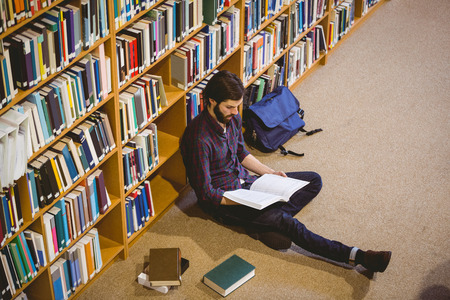 Student reading book in library on floor at the universityの写真素材