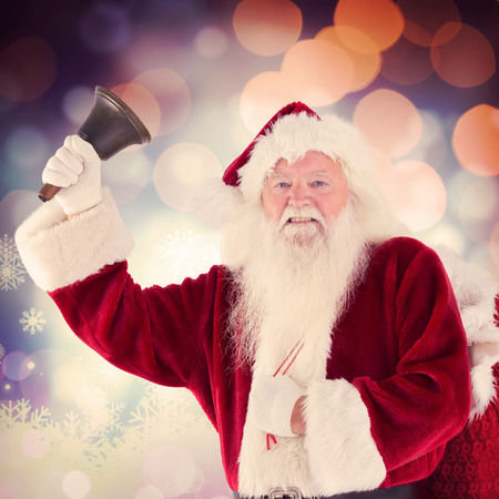Happy santa ringing a bell against glowing christmas backgroundの写真素材