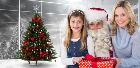 Mother and daughter with santa claus against home with christmas treeの写真素材