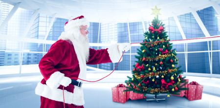 Santa pulls something with a rope against home with christmas treeの写真素材