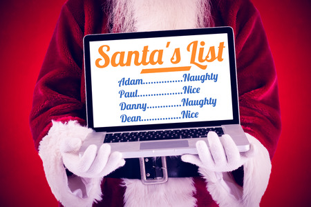 Santa Claus presents a laptop against red backgroundの写真素材