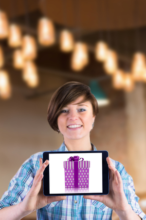 Smiling woman showing digital tablet with blank screen against purple and silver gift boxの写真素材