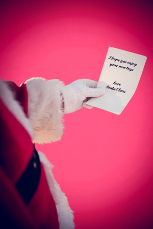 Father christmas holding a paper against red backgroundの写真素材