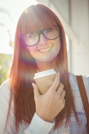 SMiling woman holding a cup of coffee outsideの写真素材