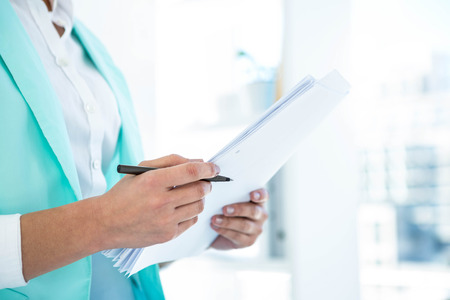 Businesswoman using her notes at the desk in workの写真素材