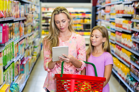 Mother and daughter checking list at the supermarketの写真素材
