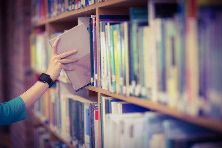 Students hand with smartwatch picking book from bookshelf at the university