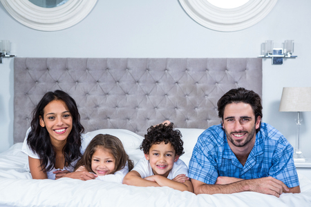 Portrait of smiling family laying on the bed at homeの写真素材