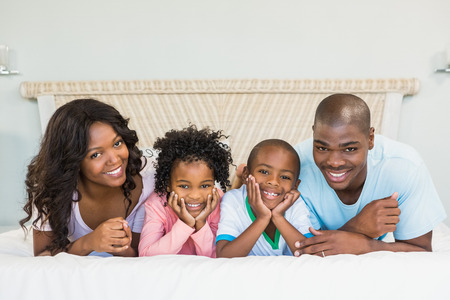 Happy family lying on bed at homeの写真素材