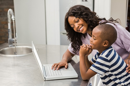 Mother and son using laptop in the kitchenの写真素材