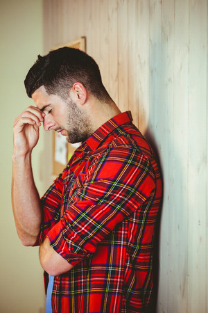 Handsome hipster feeling stressed out on wooden backgroundの写真素材