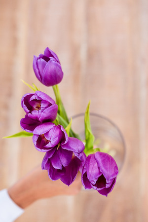 Woman putting a flowers in a vase on deskの写真素材